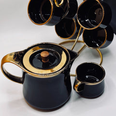 Black teapot with gold accents and matching cups on a white background